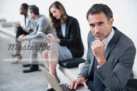 Portrait serious corporate businessman using laptop