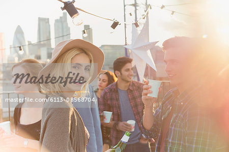 Portrait smiling young woman drinking beer at rooftop party