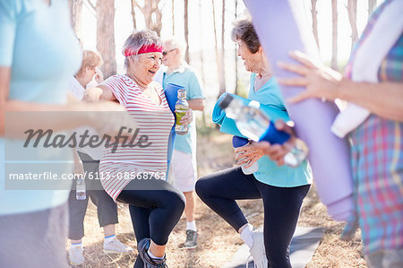 Senior women practicing yoga tree pose in park Senior women practicing yoga tree pose in park