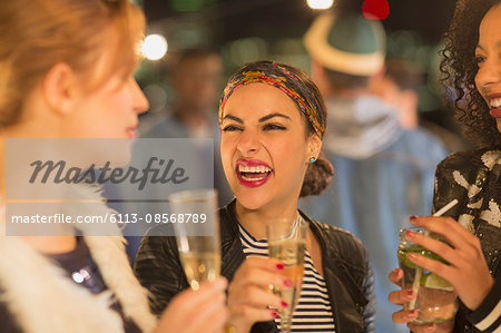 Enthusiastic young women drinking champagne and laughing at party
