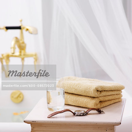 Side Table in Bathroom with Towels, Glass of Water and Watch