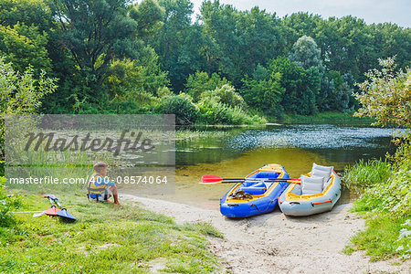 Active boy resting after adventurous experience kayaking on the river on a sunny day during summer vacation