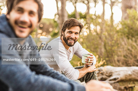 Two men drinking coffee whilst sitting in forest, Deer Park, Cape Town, South Africa