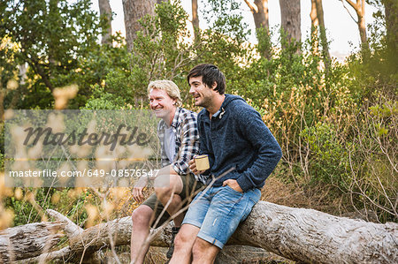 Two hikers leaning against fallen tree in forest, Deer Park, Cape Town, South Africa