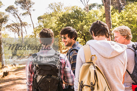 Rear view of man talking on smartphone whilst hiking with friends in forest, Deer Park, Cape Town, South Africa