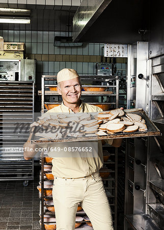 Happy baker placing tray of sliced bread into oven