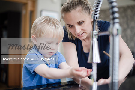 Mother helping son wash his hands