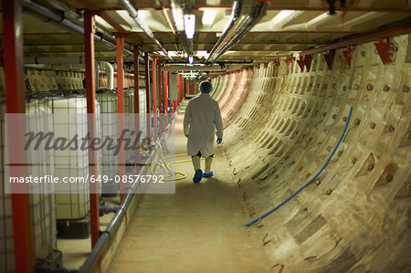 Full length rear view of worker walking down corridor wearing hair net and disposable overshoes