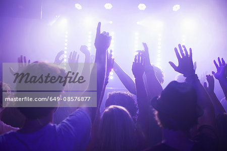 Rear view of group in club arms raised watching concert Rear view of group in club arms raised watching concert