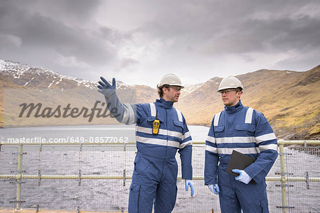 Workers on dam with water at hydroelectric power station