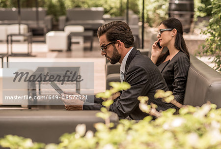Businessman using digital tablet on hotel garden sofa, Dubai, United Arab Emirates