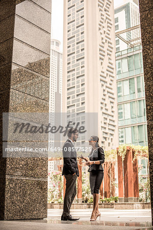 Businessman and woman talking outside office, Dubai, United Arab Emirates