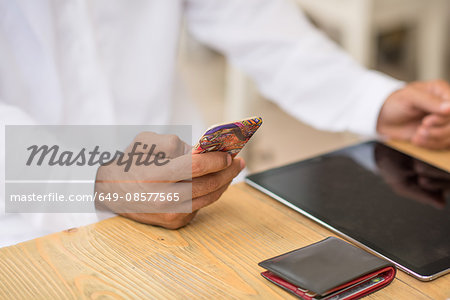 Close up of middle eastern man's hands using smartphone at cafe, Dubai, United Arab Emirates