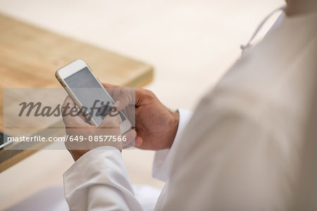 Close up of middle eastern man's hands using smartphone touchscreen at cafe, Dubai, United Arab Emirates