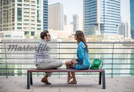 Tourist couple sitting on waterfront talking, Dubai, United Arab Emirates