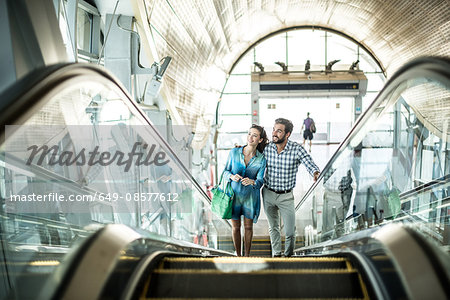 Tourist couple moving up escalator in shopping mall, Dubai, United Arab Emirates