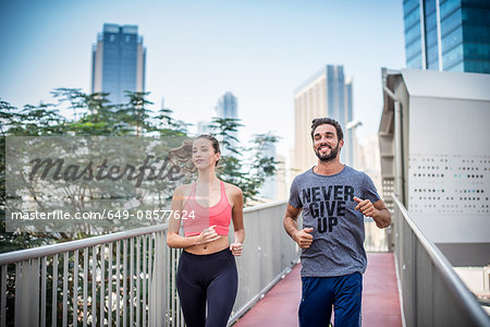 Running couple running on footbridge, Dubai, United Arab Emirates