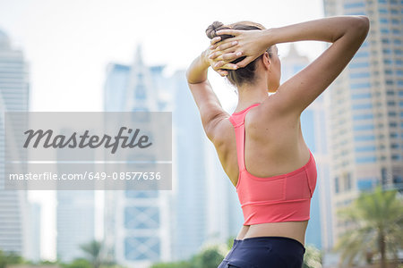 Woman training, twisting with hands behind head in park, Dubai, United Arab Emirates