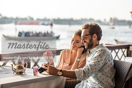 Romantic couple reviewing camera at Dubai marina cafe, United Arab Emirates