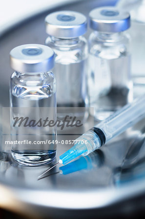 Injectable medications. Kidney dish with injectable medications in sealed vials and a disposable plastic medical syringe