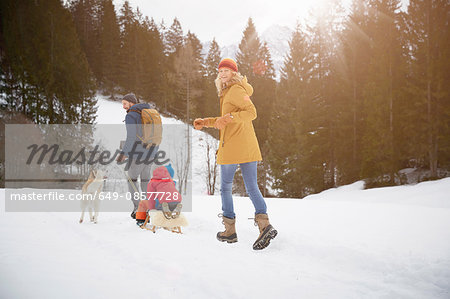 Rear view of parents pulling sons on toboggan in snow  covered landscape, Elmau, Bavaria, Germany