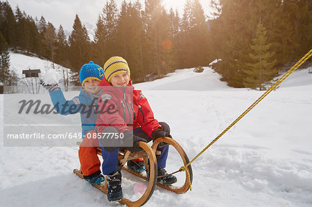 Boy and brother being pulled on toboggan in snow, Elmau, Bavaria, Germany