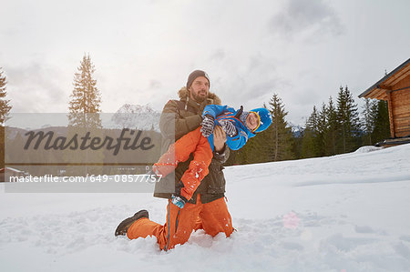 Father lifting up son in snow, Elmau, Bavaria, Germany