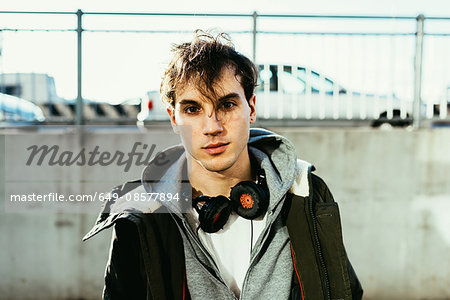 Portrait of man wearing hooded top and head phones looking at camera