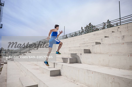 Young male runner running up stairway