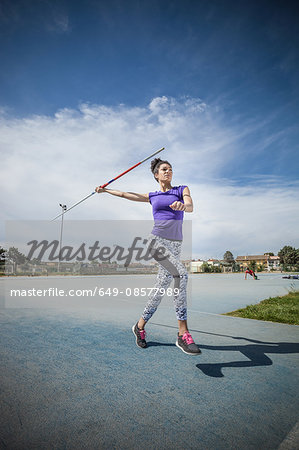 Young woman throwing javelin in sports ground