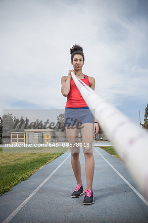 Portrait of young female pole vaulter concentrating at sport facility
