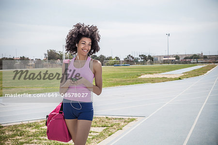 Young woman training, listening to earphones on running track