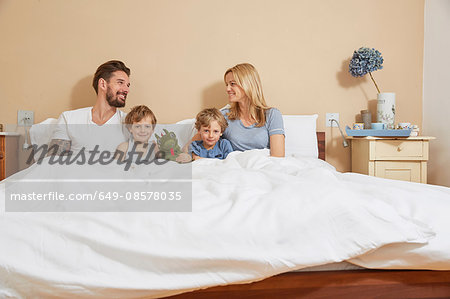 Mother and father in bed with sons and toy dragon