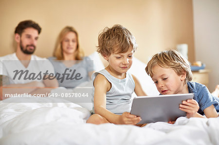 Boys on parents bed using digital tablet