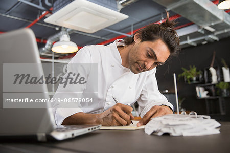 Chef in restaurant writing in notepad