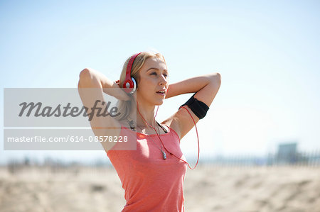 Young woman outdoors, wearing headphones and activity tracker