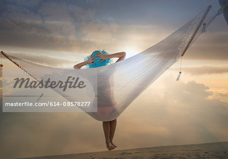 Rear view of young woman lying on hammock at sunset, Miami beach, Florida, USA