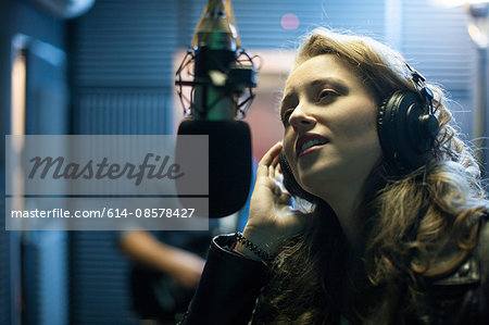 Female musician in recording studio, singing into microphone Female musician in recording studio, singing into microphone