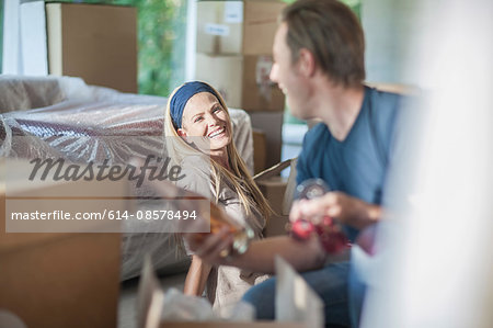 Moving house: couple in room with cardboard boxes, man holding bottle of champagne and champagne flutes