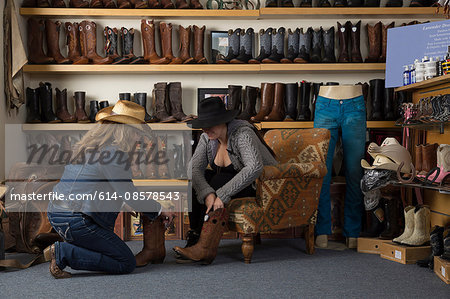 Shop assistant helping customer with boots