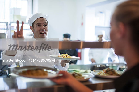 Waitress taking meal off kitchen counter for customer