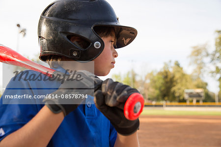 Close up of boy preparing to bat at practise on baseball field