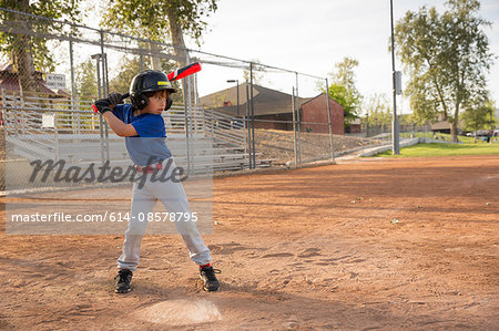 Boy batting at practise on baseball field