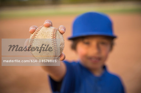 Blurred portrait of boy holding up ball at baseball practise