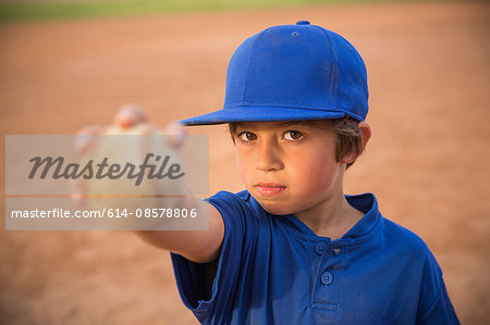 Portrait of boy holding up ball at baseball practise