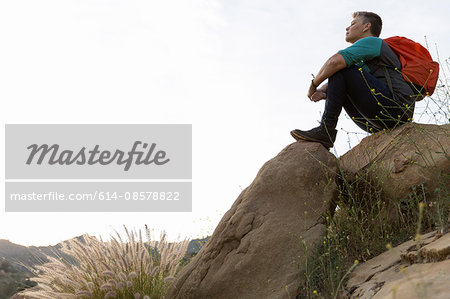 Woman hiker sitting on top of rocks looking away