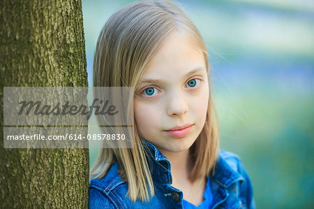 Portrait of blond haired girl leaning against tree in bluebell forest, Hallerbos, Brussels, Belgium