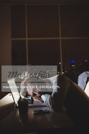 Businessman sleeping on his laptop at night