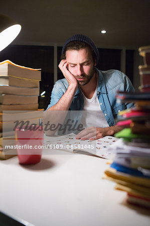 Hipster reading a document with stacks of books