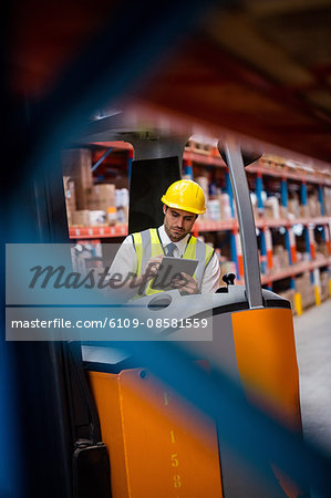 Warehouse manager with clipboard in forklift